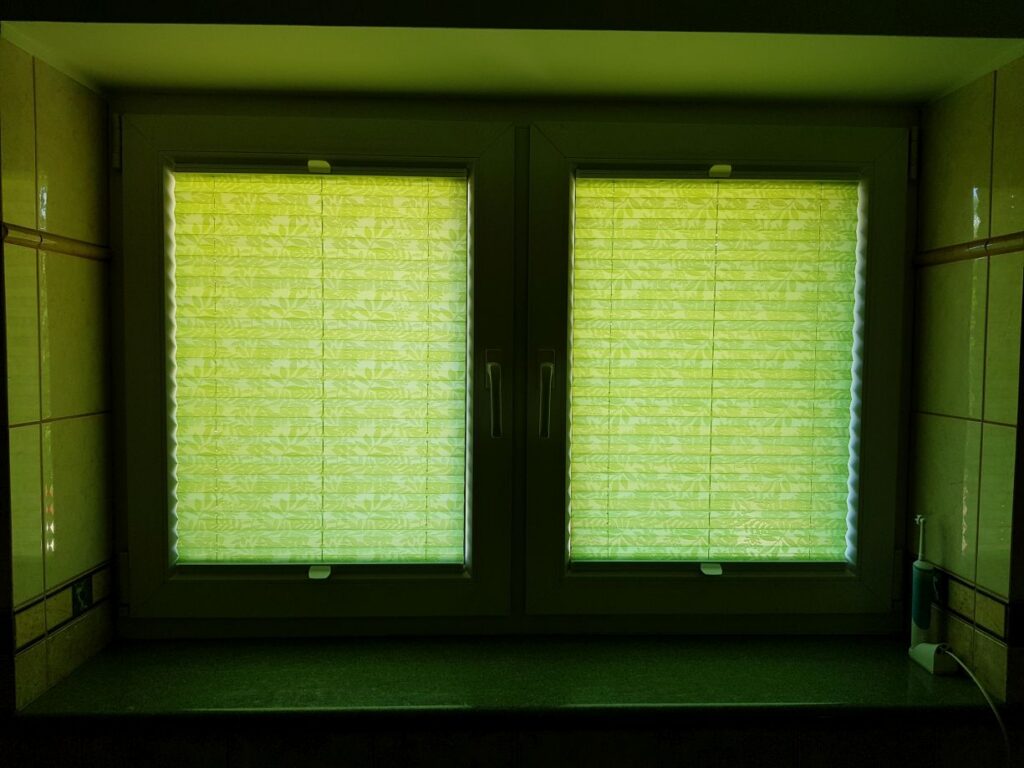 plisy, profil biały, materiał  półprzezroczysty kolor zielony ze wzorem w liście